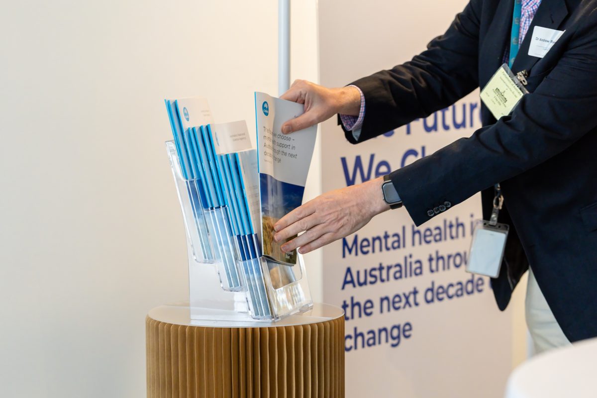 • Hand taking a report: A guest lifting a copy of the report from the acrylic display stand during the launch.
