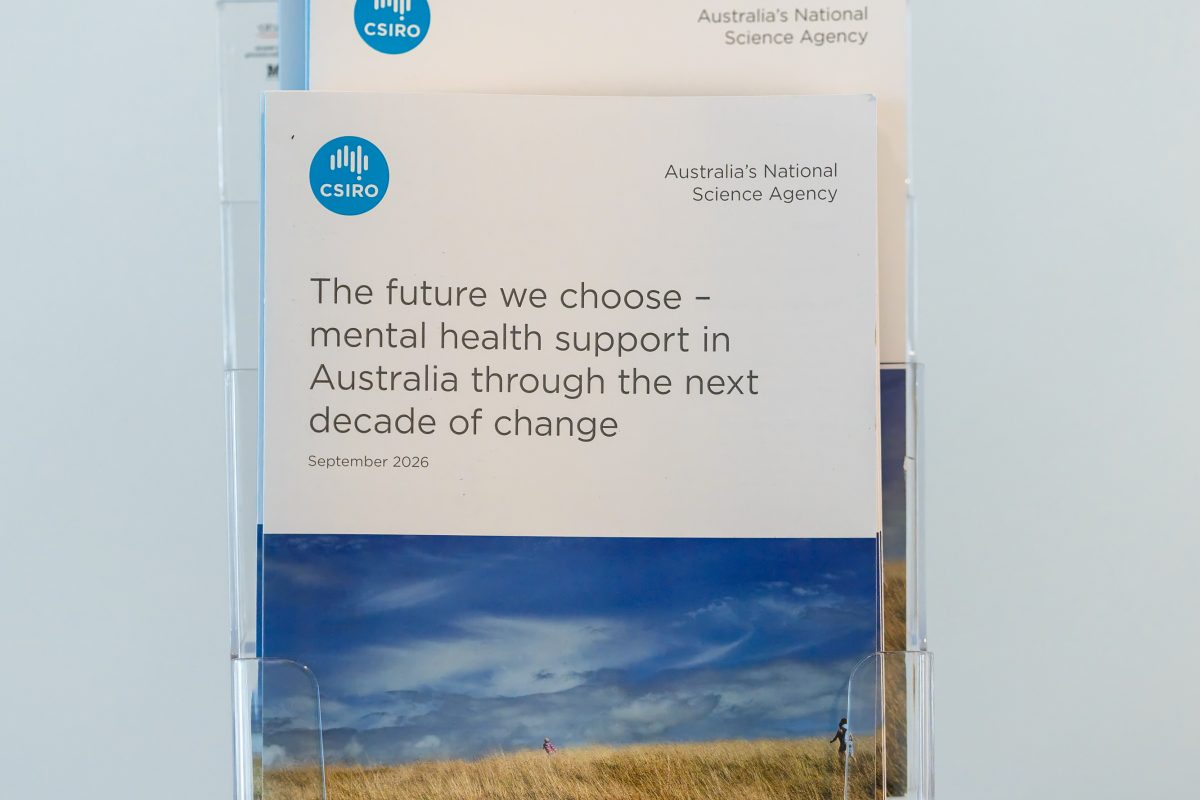 • Report display detail: Printed copies of The Future We Choose in an acrylic holder, the cover showing coastal grassland under a wide sky.