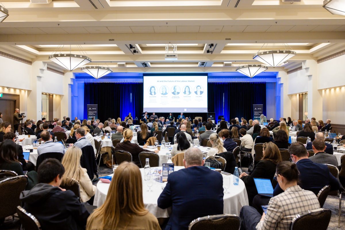 The Federation Ballroom at capacity for the panel on AI and the future of the labour market, with the five panellists on stage and their names on the main screen.