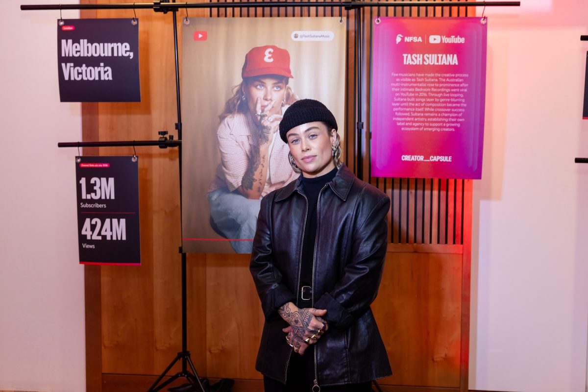 • Creator stations at the Creator Capsule launch, lit in magenta and red, with hanging panels showing a creator portrait, channel statistics and a written biography on freestanding rigs set in front of the room’s existing framed artworks.