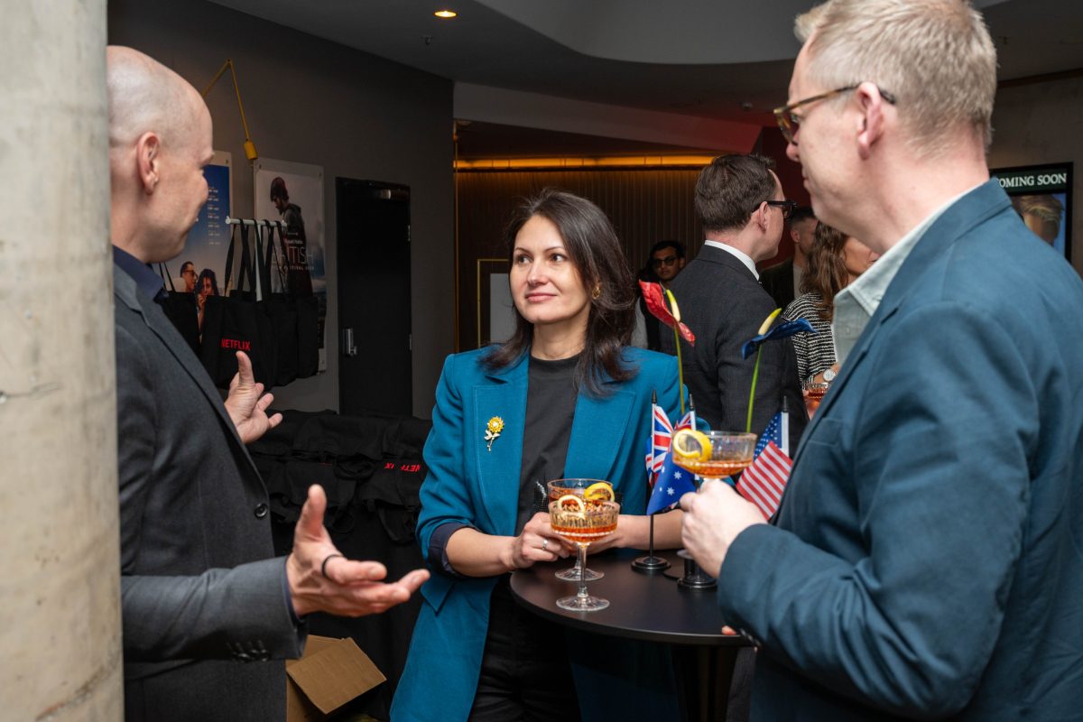 Guests mingling around cocktail tables styled with international desk flags at the Netflix The Diplomat launch in Canberra